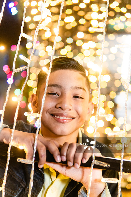 夜晚，男孩在节日的灯光下快乐地玩耍图片素材