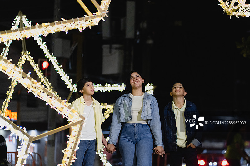 拉丁裔兄弟姐妹在夜晚的灯光下享受灯会图片素材