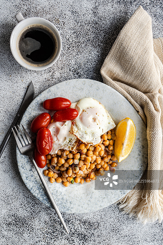 鹰嘴豆沙拉俯视图，配有红洋葱、石榴、香菜、煎蛋、番茄和一杯黑咖啡图片素材