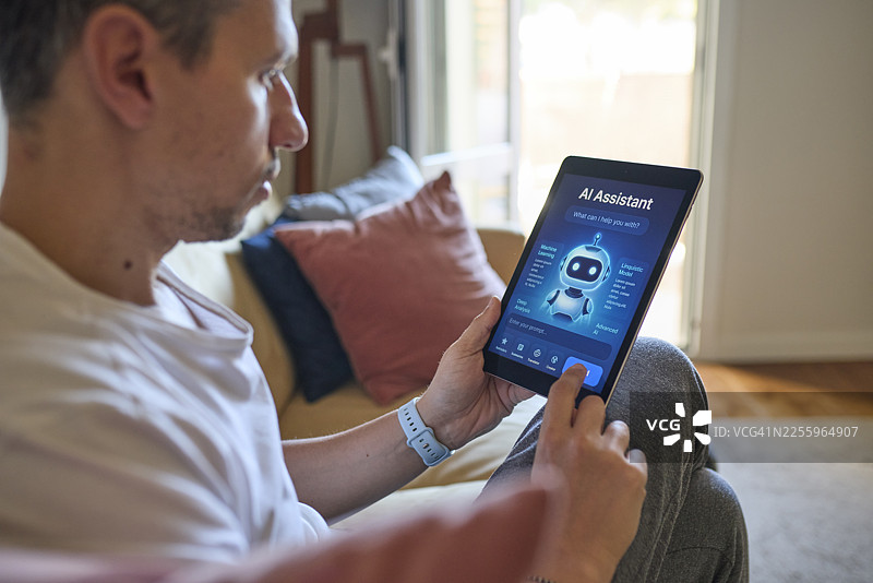 侧面视角，一个人在家中舒适地坐在沙发上，在平板电脑上使用人工智能助手。图片素材