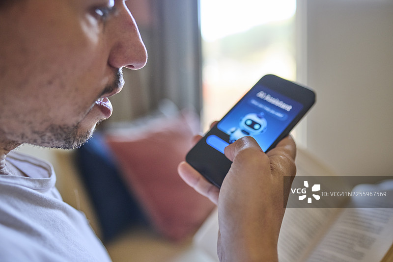 侧面视角：男人在智能手机上使用语音指令与AI助手互动图片素材