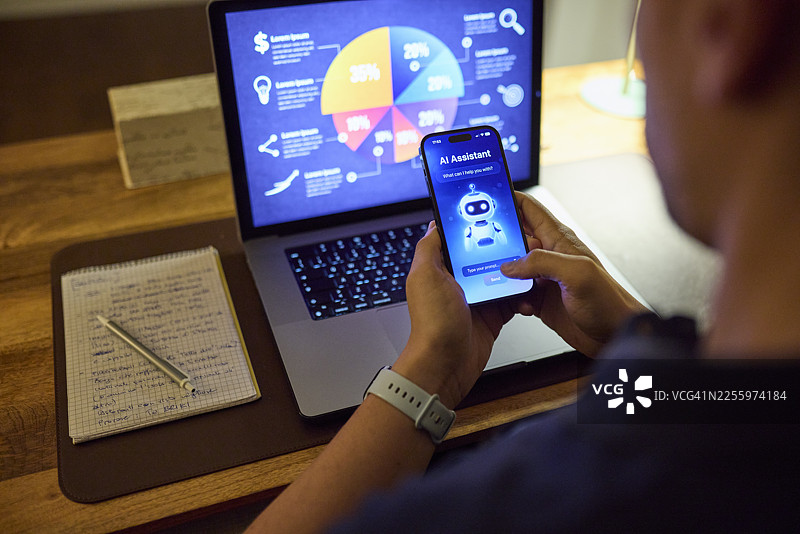 夜间在家中，一名男子在笔记本电脑和智能手机上，借助人工智能助手分析数据图片素材