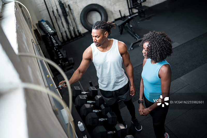 中年黑人女性在现代健身房与私人教练一起训练图片素材
