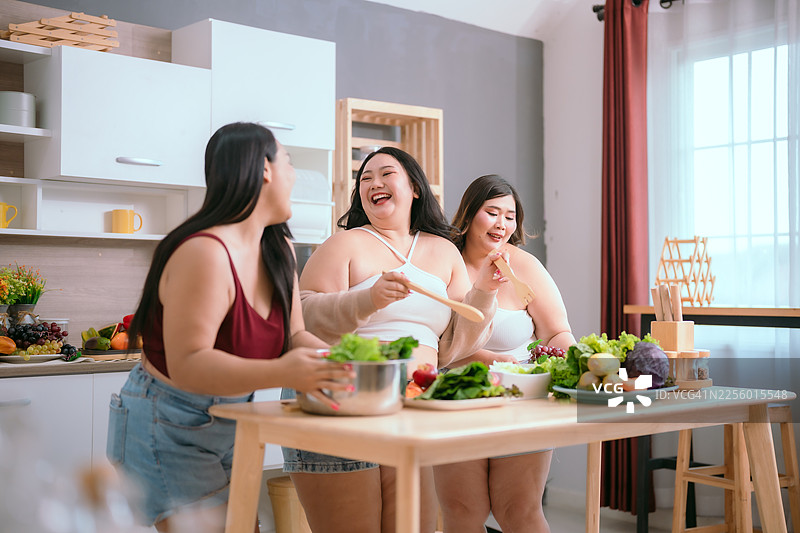 朋友们在现代厨房里，伴着新鲜蔬菜的清香和午间的欢笑，一同享受烹饪的乐趣。图片素材