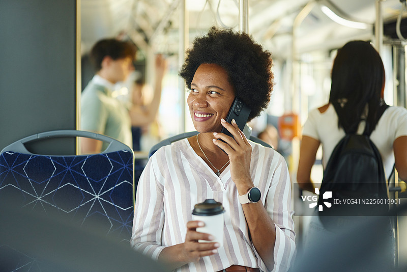一位快乐的黑人女性在公共交通工具上用手机交谈。图片素材