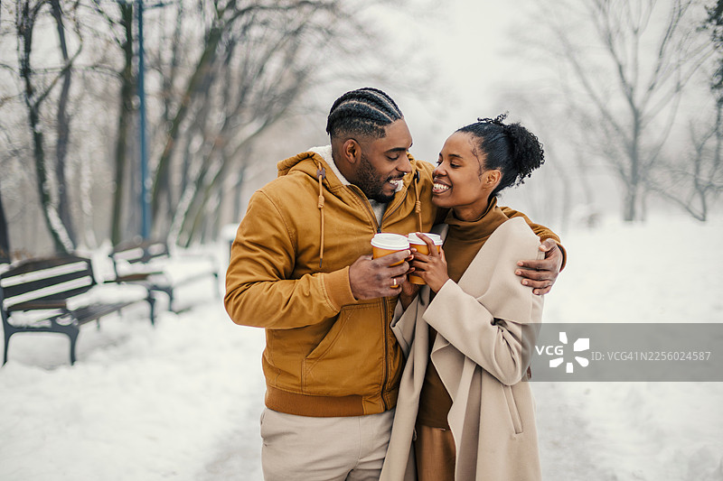 一对快乐的情侣在冬日的公园里享用热咖啡图片素材