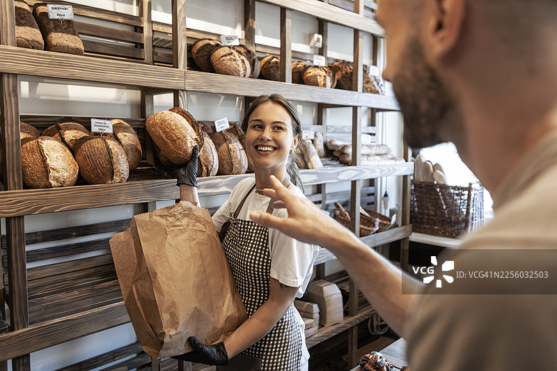 友好的面包师展示新鲜出炉的面包图片素材