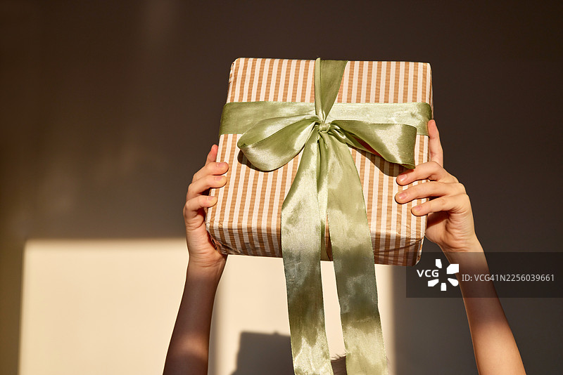 一个人拿着带有绿色丝带的条纹礼品盒图片素材