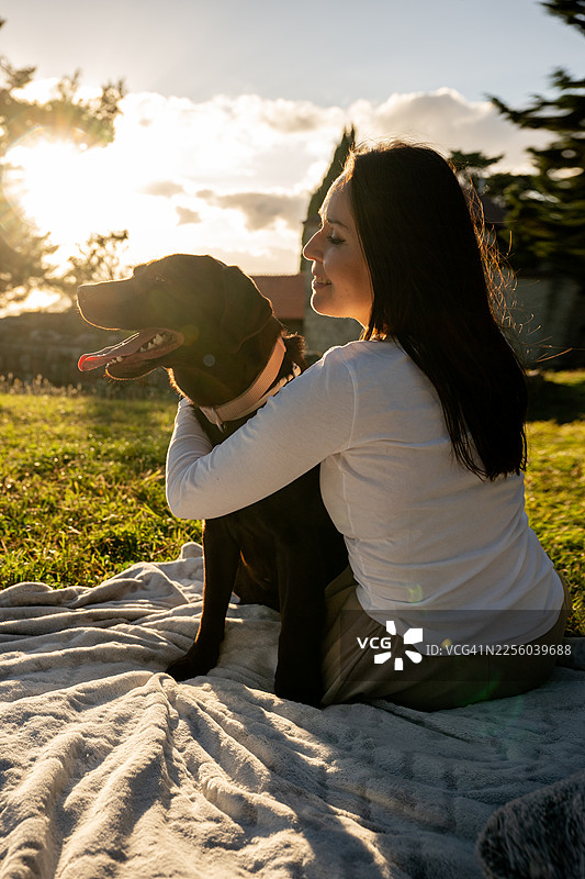 金时日落时拥抱拉布拉多犬的女人图片素材