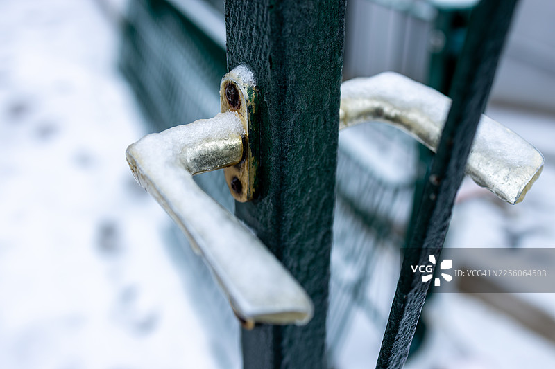 冬日里，金属门把手上覆盖着霜和雪的特写图片素材
