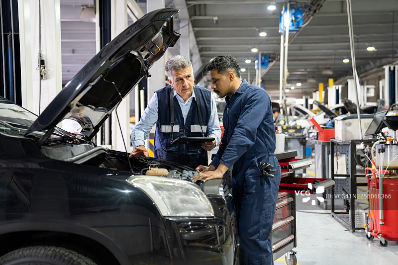 技师团队正在车库里修理汽车，掀开发动机盖进行检查图片素材