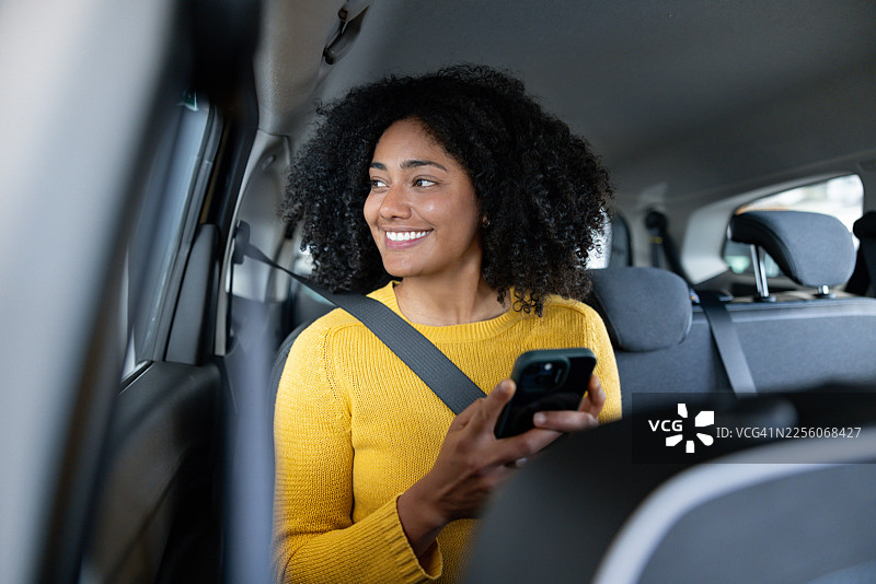 女子在网约车上，同时看着手机图片素材