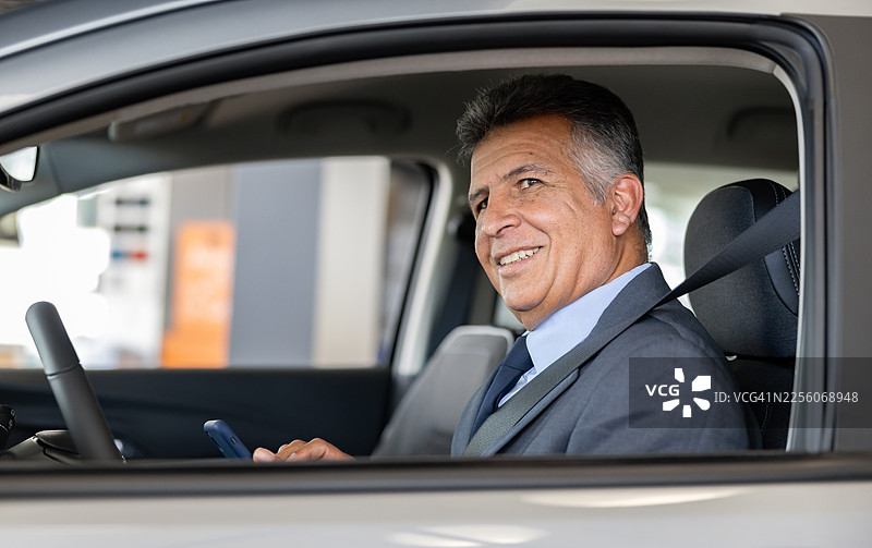 快乐的众包出租车司机拿着手机，面带微笑图片素材