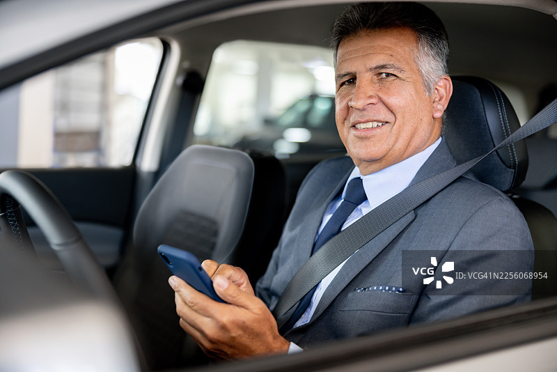 快乐的众包出租车司机拿着手机对着镜头微笑图片素材