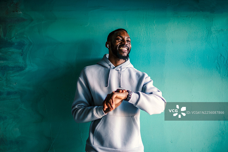 快乐的男人正在查看智能手表，他微笑着看向别处图片素材