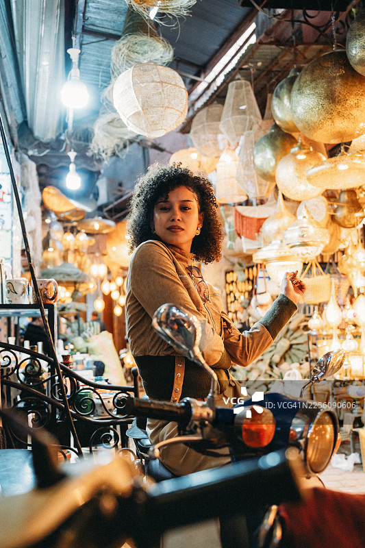 年轻女子在马拉喀什的市集里骑着滑板车摆姿势图片素材