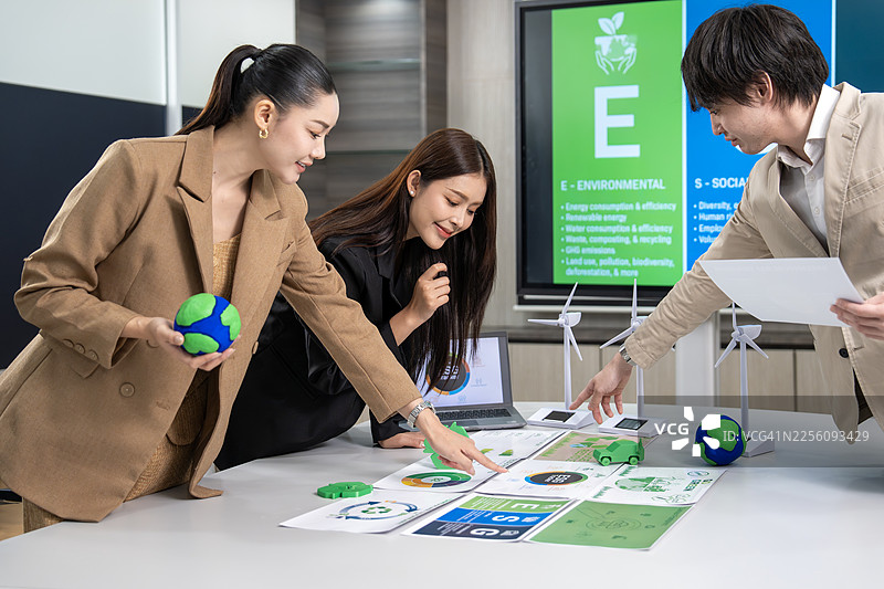 多元化的商务团队在办公室围坐在笔记本电脑旁开会，讨论涉及太阳能和风能的可持续设计方案。 环保商务团队讨论ESG目标。图片素材