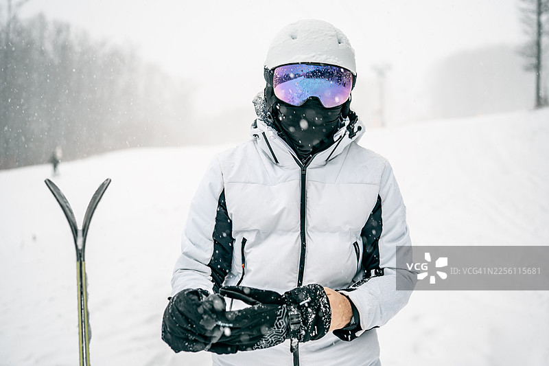 身穿白色夹克和滑雪装备的冬季运动爱好者站在雪景中图片素材