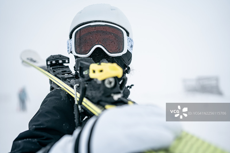 滑雪者戴着白色头盔和护目镜，伸出手持雪杖，在雪地上进行特写图片素材