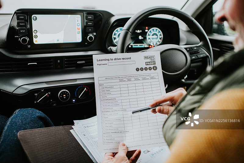 一位驾驶教练在第一次驾驶课上，带领新学员核对指导说明清单。图片素材