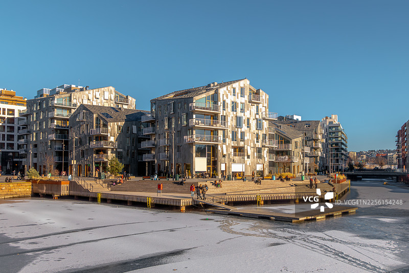 奥斯陆比约维卡现代化的滨水公寓楼，人们在阳光明媚的冬日享受生活图片素材