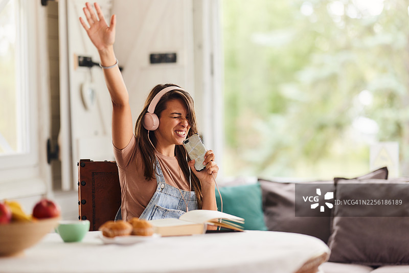 在家，女子无忧无虑地用手机听音乐。图片素材