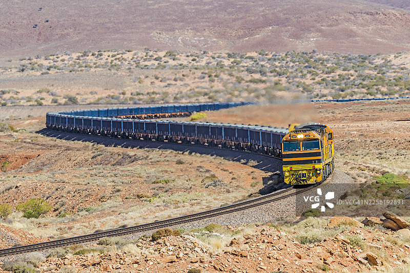 载有蓝色集装箱的货运火车驶向偏远地区的装货点，准备装载铁矿石图片素材