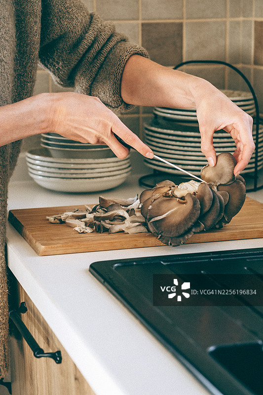 切板上切牡蛎蘑菇的手图片素材
