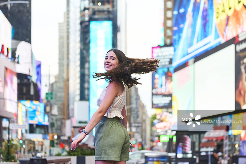 年轻女子在时代广场，甩着头发，面带微笑图片素材