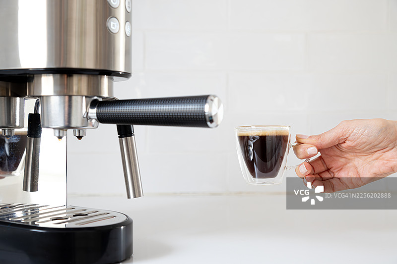 一个人拿着咖啡杯，从咖啡机中接收浓缩咖啡图片素材