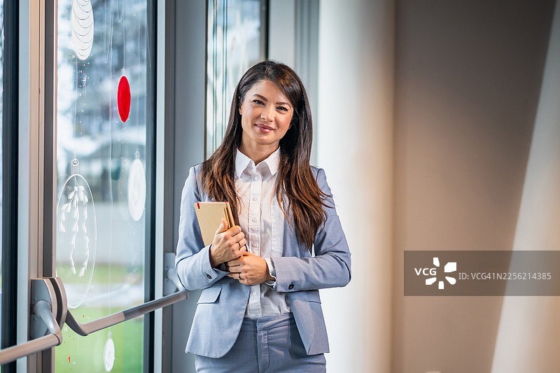 自信的女商人微笑着，手里拿着一本书图片素材