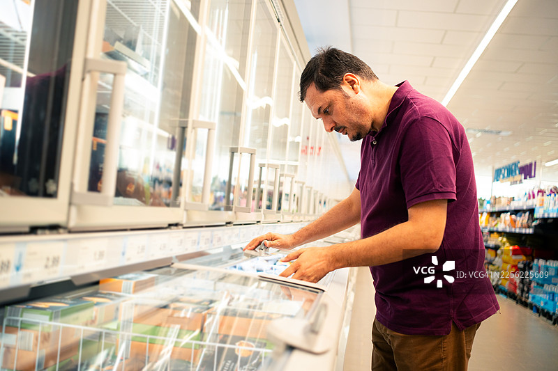 男士在超市挑选冷冻食品图片素材