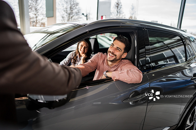 一对快乐的夫妇在购买新车时握手图片素材