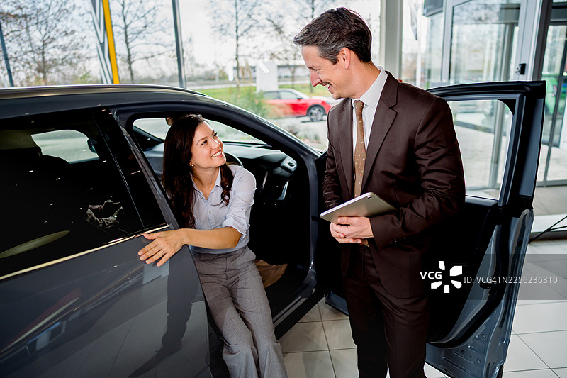 销售人员在经销商处向女性顾客展示汽车图片素材