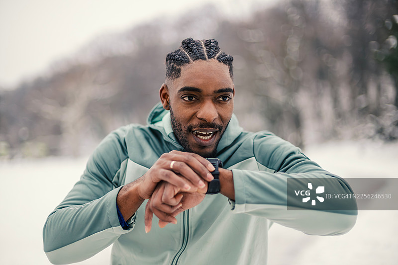 男性运动员在冬季公园锻炼时查看智能手表图片素材
