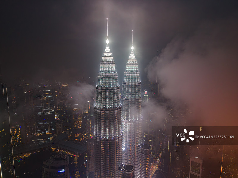吉隆坡佩特罗纳斯双子塔在夜雾中闪耀的鸟瞰图图片素材