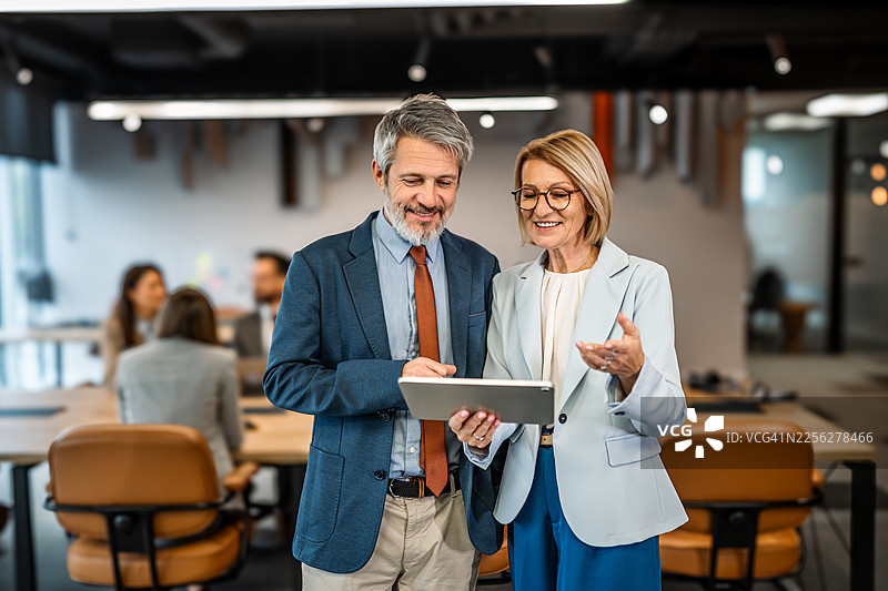 办公室里，商务同事们在数字平板上协同工作图片素材