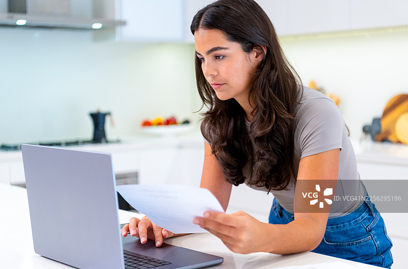年轻女子在厨房处理文件或家庭财务图片素材
