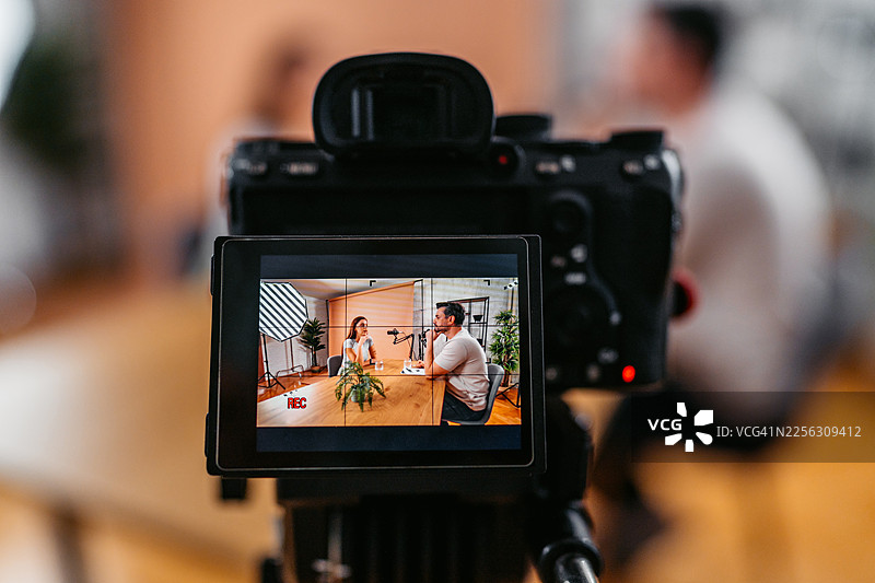 播客录音室里，一位男主持人与一位女嘉宾对着麦克风交谈图片素材