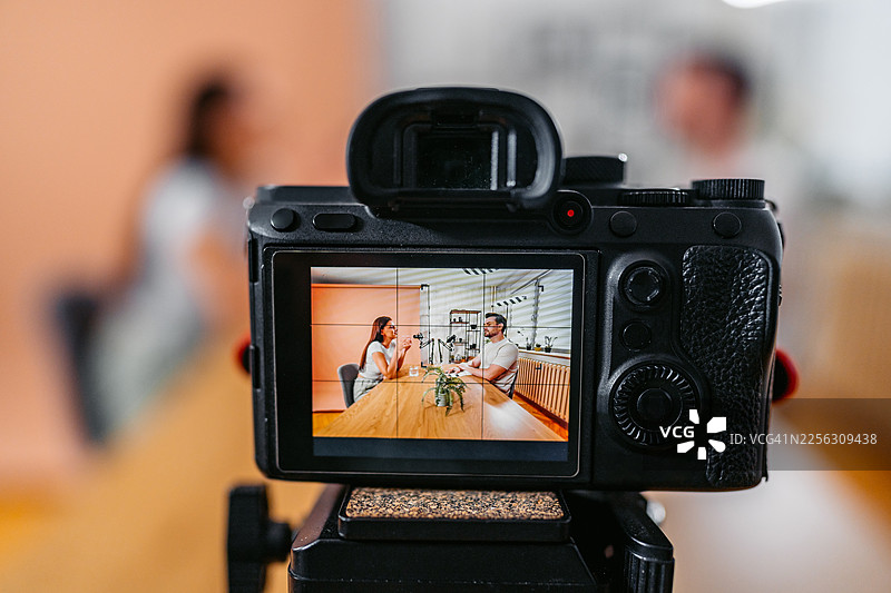 播客录音室里，一位男主持人与一位女嘉宾正在对着麦克风交谈图片素材