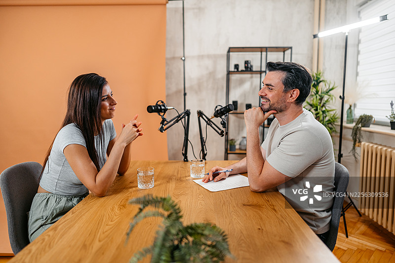 播音室里，一位男主持人与一位女嘉宾正在对着麦克风交谈图片素材