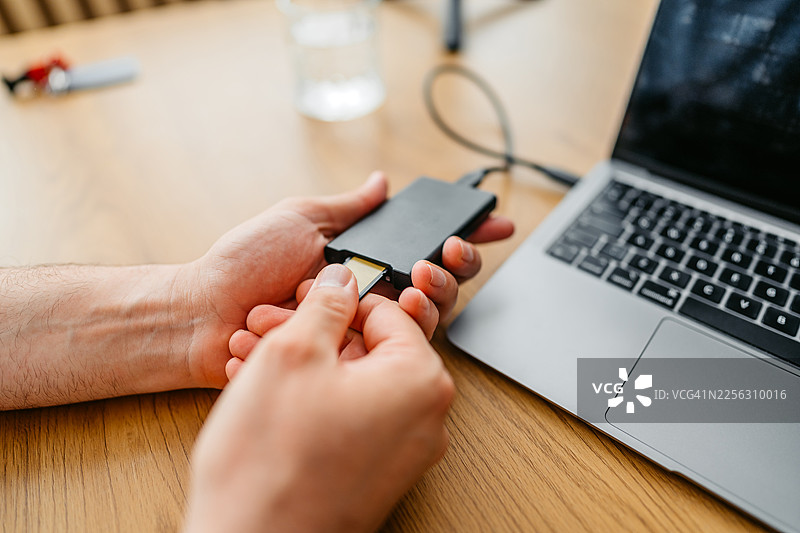 男摄影师在影棚的笔记本电脑上转移数据图片素材