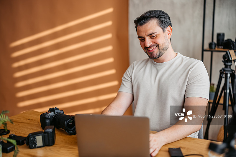 男摄影师在工作室的笔记本电脑上工作图片素材
