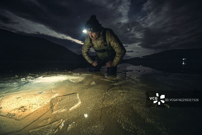 渔民在冰封的海面上探索。夜晚冬季垂钓（使用灯光）图片素材
