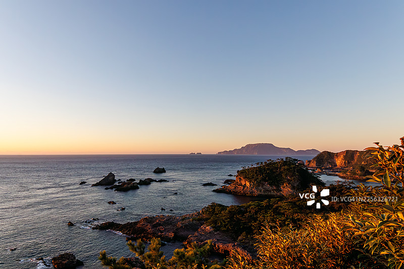 日出海景。从郡山天文台看到的伊豆群岛的美丽海景。海上可以看到新岛和神津岛。还可以看到载有乘用车的大型货船和渔船。远处是白色的石灰岩悬崖。图片素材