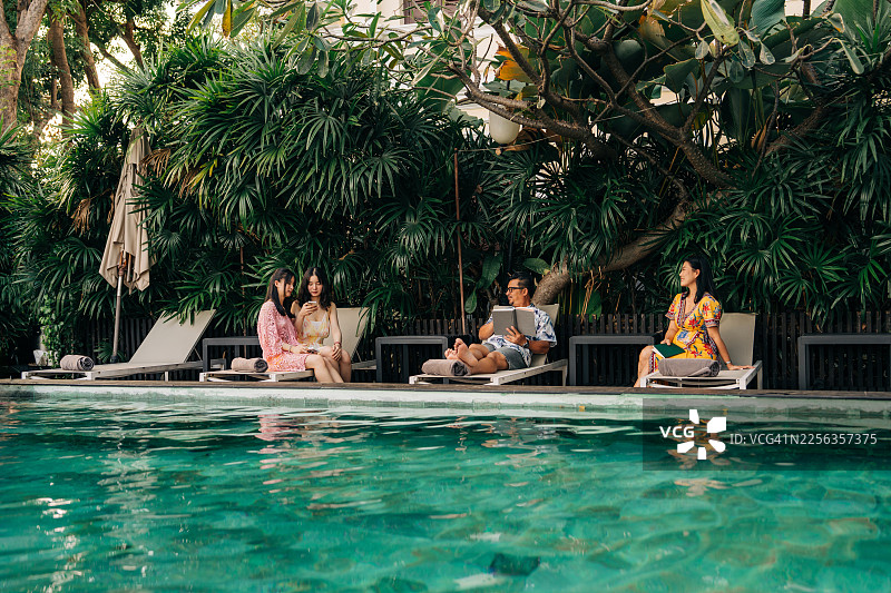亚洲家庭在豪华酒店度假村泳池边放松图片素材