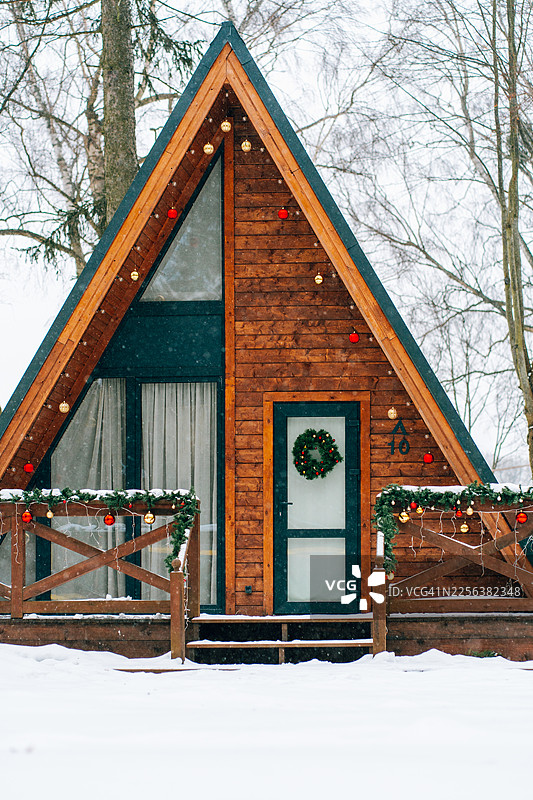 装饰一新的A型小屋，充满冬日节日气氛，屋外飘着雪花图片素材