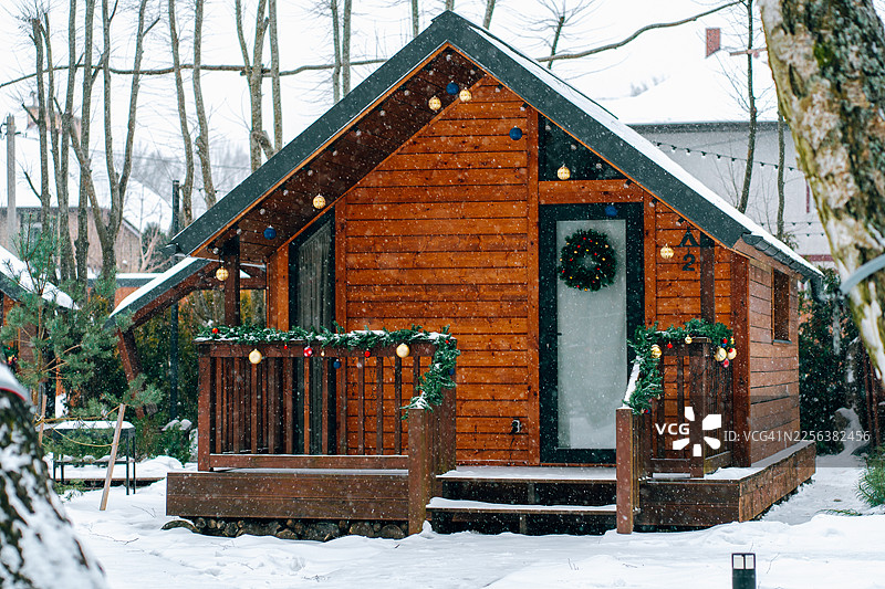 温馨的木屋，装饰着冬日假日，伴随飘落的雪花图片素材