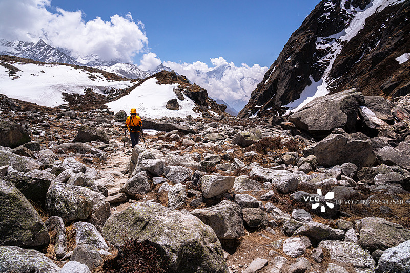 一名穿着徒步服装、携带装备的游客,在尼泊尔喜马拉雅山脉的戈吉奥湖徒步路线上,于晴朗的一天中,在极端地形的足迹小径上徒步旅行。图片素材