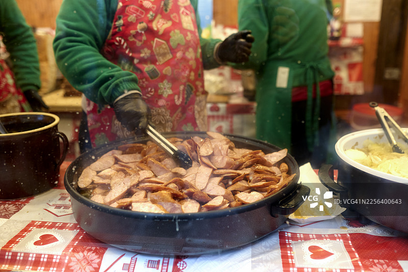 波兰弗罗茨瓦夫，市集摊位上烹饪香肠的女子图片素材